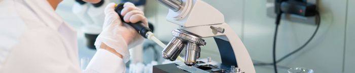 A woman doing laboratory testing with a microscope