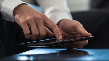 Businessman navigating a tablet computer with a finger while scrolling the internet.